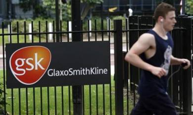 A jogger runs past a signage for pharmaceutical giant GlaxoSmithKline